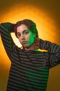 Portrait of young woman standing against yellow background