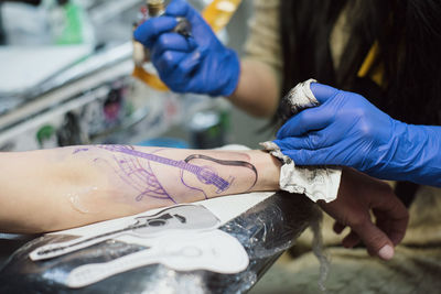 Artist tattooing on hand at studio