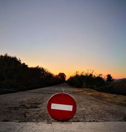 Road sign against clear sky during sunset