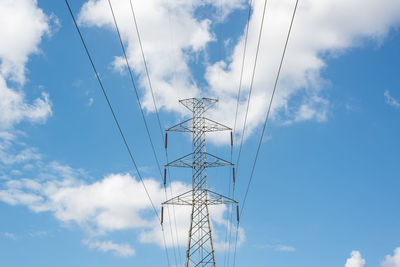 Low angle view of electricity pylon against blue sky