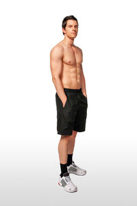 Full length of shirtless man standing against white background