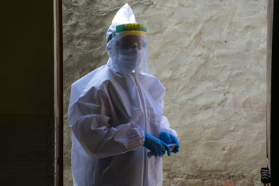 Portrait of woman wearing protective suit standing against wall