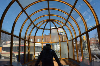 Rear view of man standing on glass window