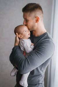Father with a beard holds a newborn in his arms on a grey background. holiday concept