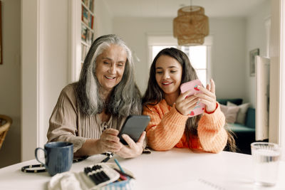 Happy grandmother and granddaughter using smart phone at home