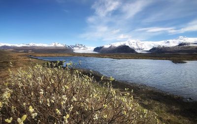 Scenic view of lake by snowcapped mountains against sky