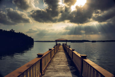 Pier over lake against sky during sunset