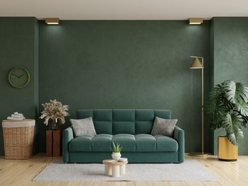 Green wall mock up in dark tones with green sofa and decoration minimal.3d rendering