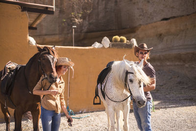 Friends preparing horses for riding