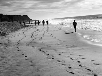 People walking on beach against sky