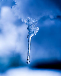 Close-up of icicles against blue sky