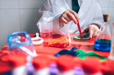 Midsection of boy doing scientific experiment on table in classroom