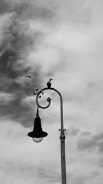Low angle view of weather vane against cloudy sky