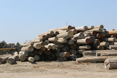 Stack of logs on field against clear sky