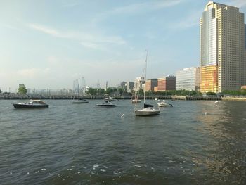 Sailboats in sea against modern buildings in city