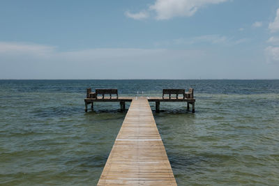 Wooden pier on sea against sky