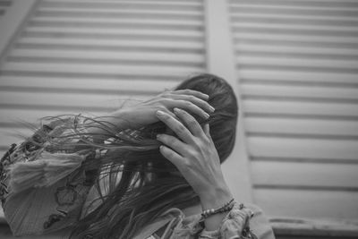 Low angle view of woman with tousled hair standing against wall