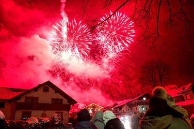 Rear view of people looking at fireworks display against sky at night