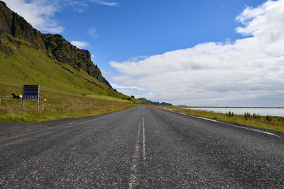 Empty road by mountain against sky