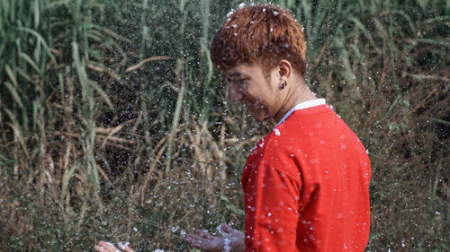 Side view of smiling man standing amidst foam against plants 