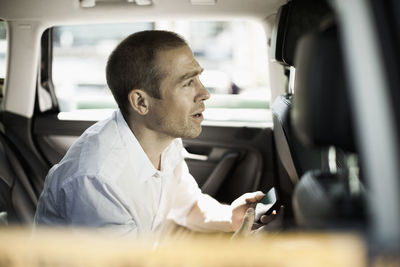 Side view of businessman with mobile phone sitting in taxi