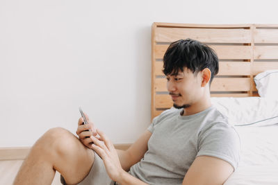 Rear view of boy sitting on bed at home