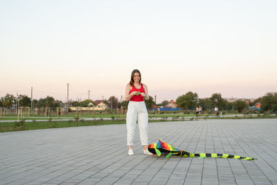 Portrait of a smiling young woman standing on tiled floor against sky