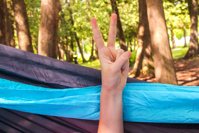 Midsection of person relaxing on hammock in forest