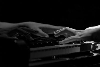 Midsection of person playing piano against black background