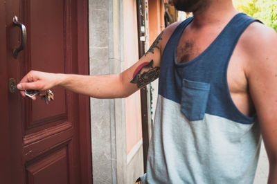 Midsection of man opening door with keys