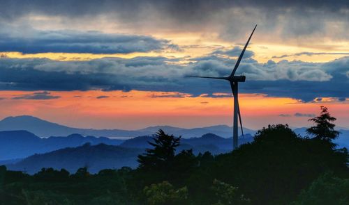 Silhouette wind turbine against sky during sunset