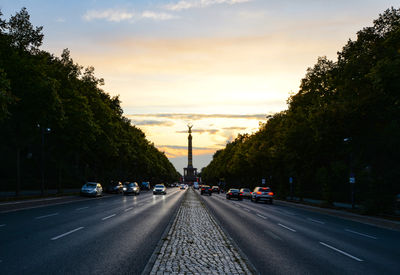 Cars on road against sky during sunset