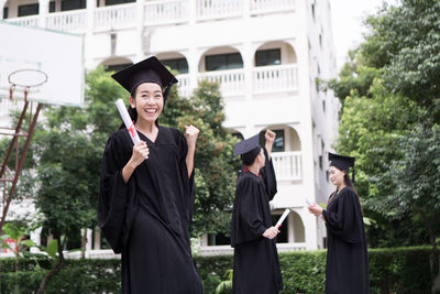 Cheerful student with clenched fist wearing graduation gown