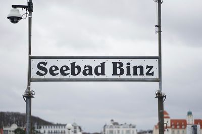 Information sign on street against sky