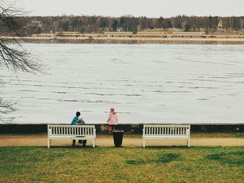 People sitting on bench by lake