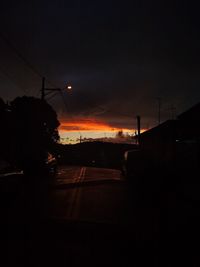 Silhouette city street against sky during sunset