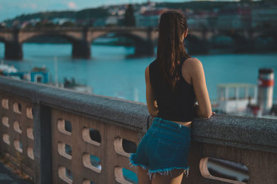 Rear view of woman on bridge over river in city