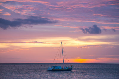 Sailboat sailing on sea against sky during sunset