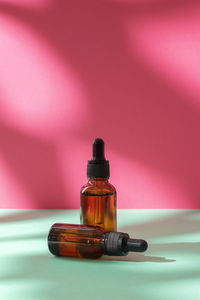 Nature cosmetic in glass bottles and shadow on pink background. face and body care 