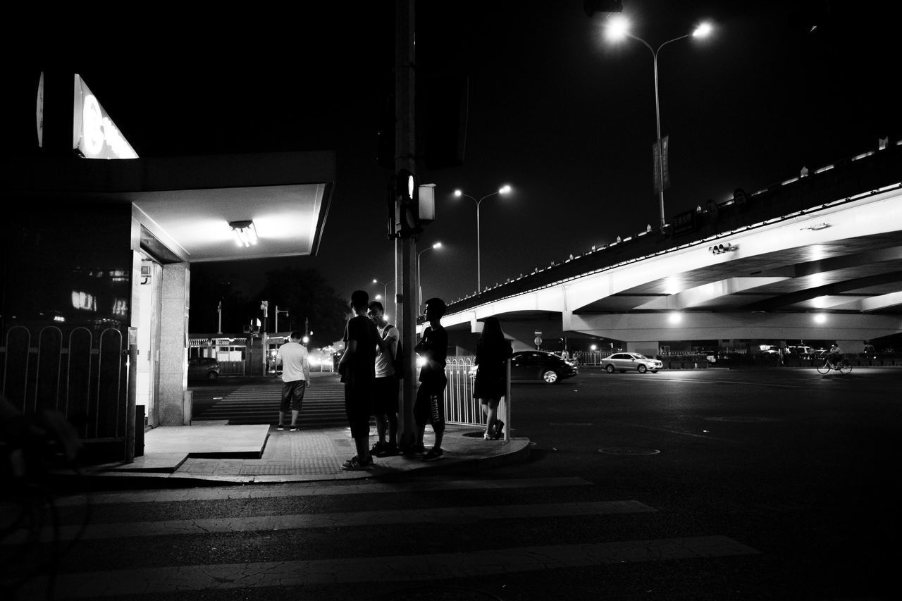 PEOPLE WALKING ON ILLUMINATED STREET LIGHT AT NIGHT