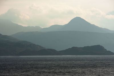 Scottish coastline. layers of hills and mountains. sun breaking through a very cloudy sky.