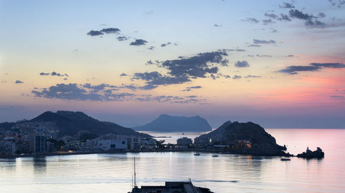 Sailboats moored in sea against sky during sunset