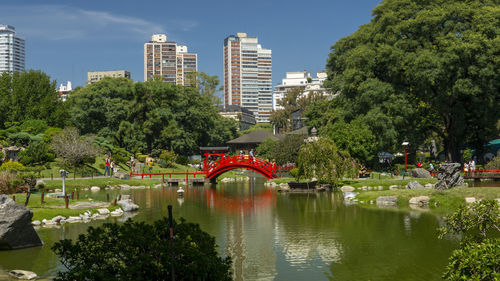 Bridge over lake by buildings in city against sky