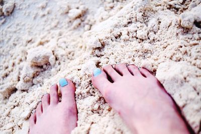 Close-up of woman legs on sand during sunny day