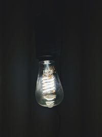 Close-up of illuminated light bulb against black background