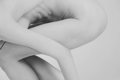 Midsection of naked woman bending over white background