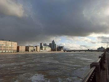 Buildings in city against cloudy sky