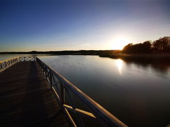 Bridge over lake against sky during sunset