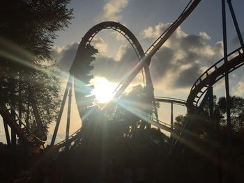 Low angle view of rollercoaster against sky during sunset