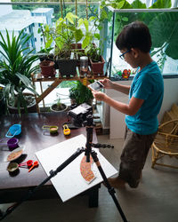 Side view of boy standing by table